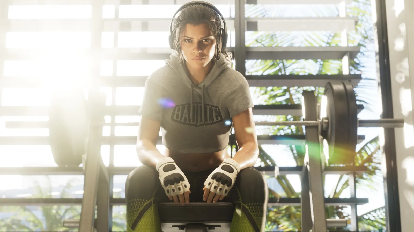 Lucia wearing training gloves and headphones while seated in a sunlit gym.